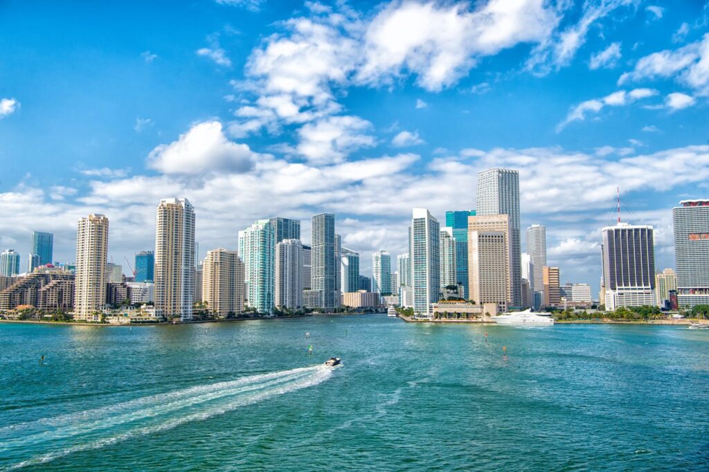 Downtown Miami skyline and the mouth of the Miami River seen across Biscayne Bay, with a boat crossing the water