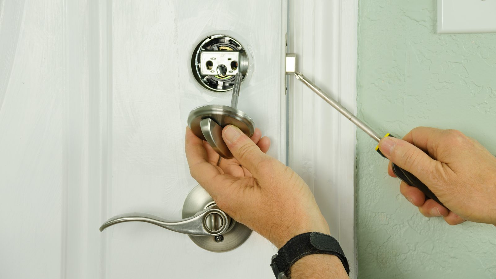 Locksmith installing a deadbolt lock on a white residential front door