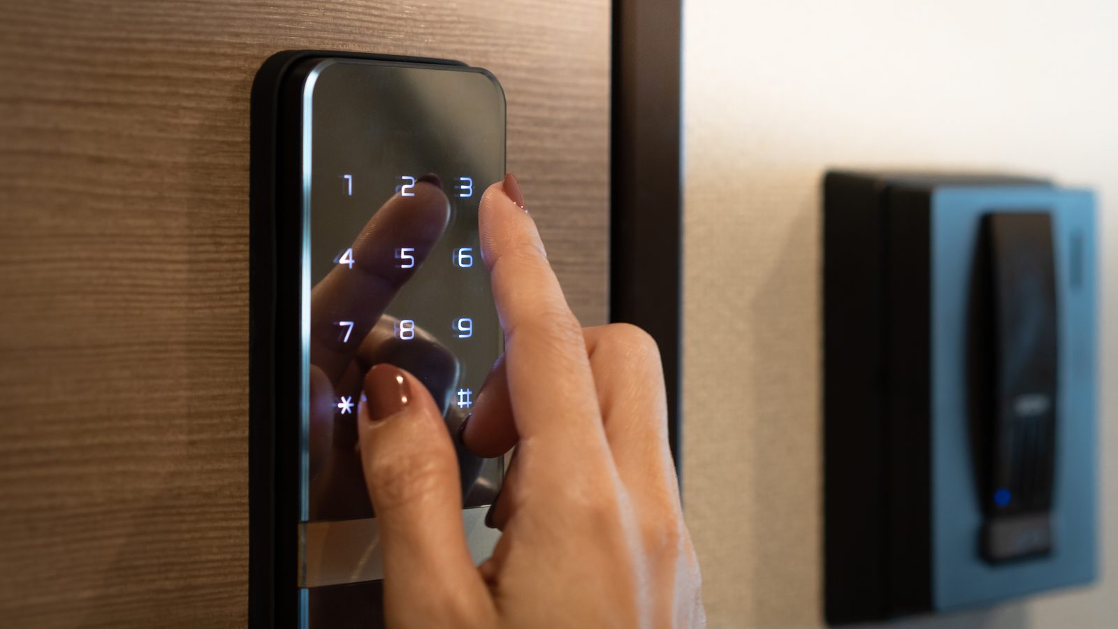Person entering a code on a keypad door lock beside a card reader at an office entrance in Miami