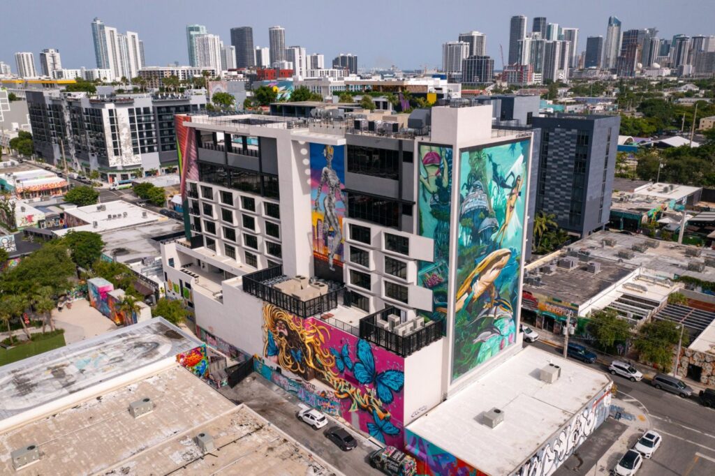 Aerial view of a mural-covered building in Wynwood, Miami with the downtown skyline behind it